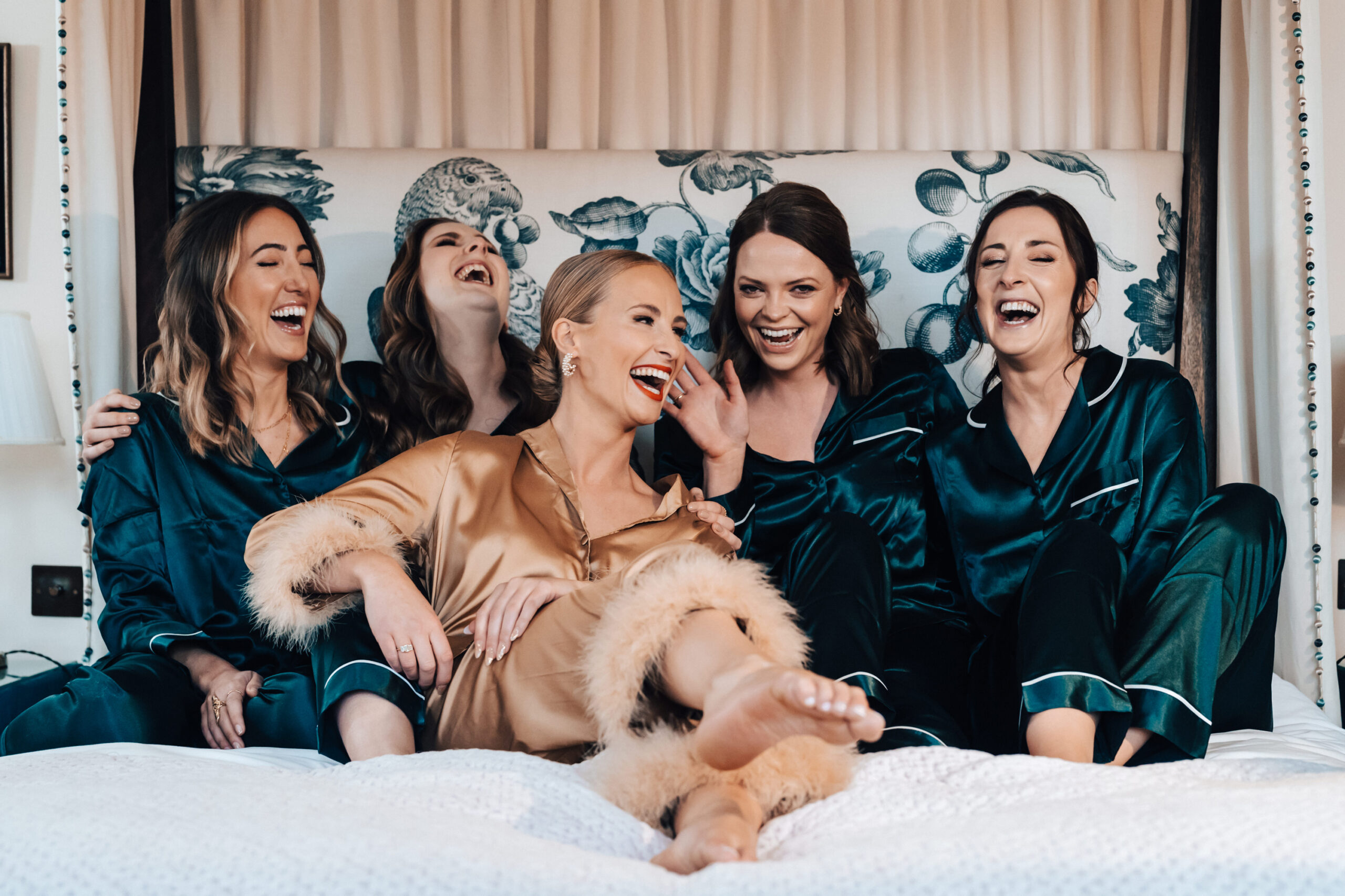 Five girls laughing wearing pyjamas in a bed