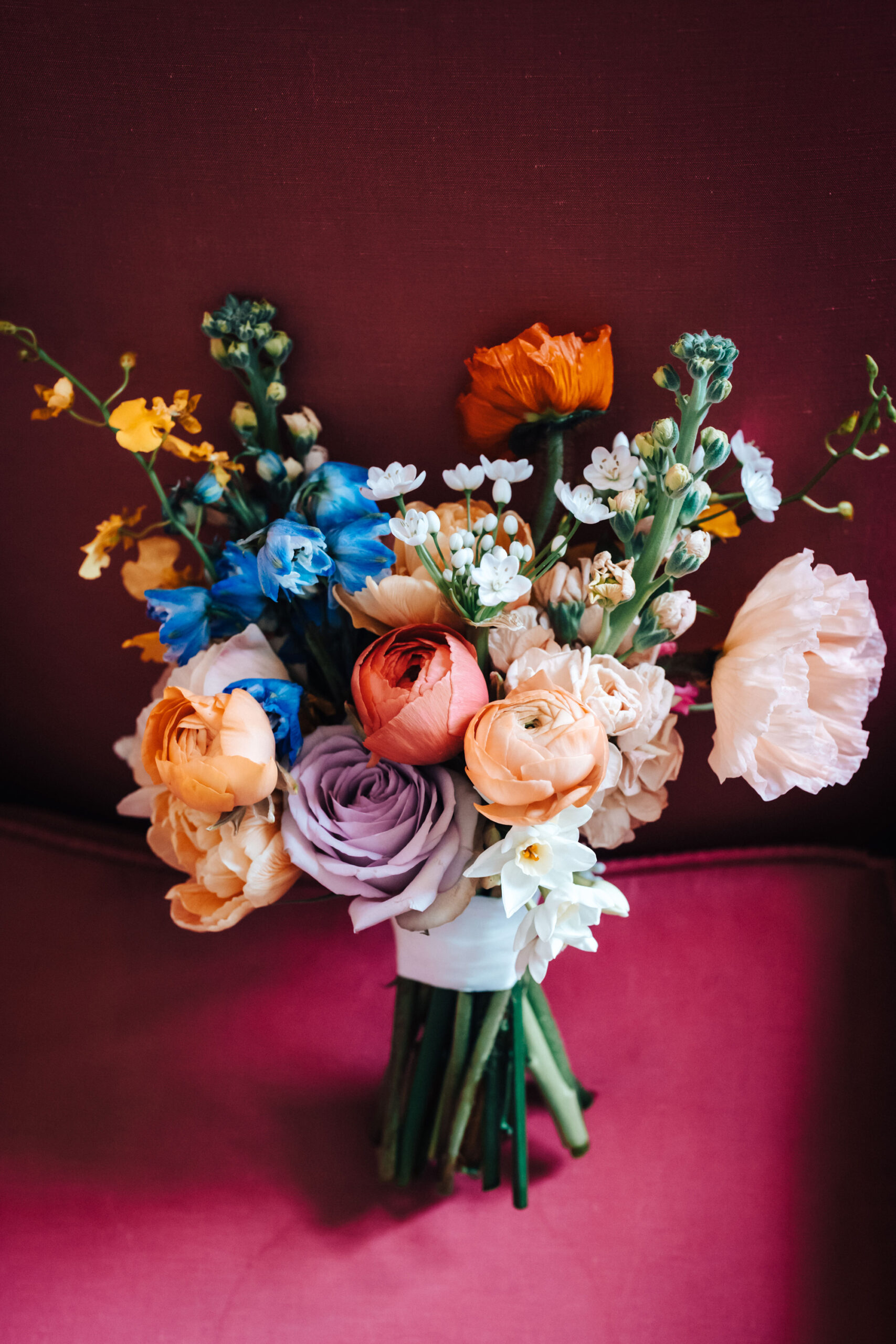 A bouquet of brightly coloured flowers including peonies, delphiniums and roses