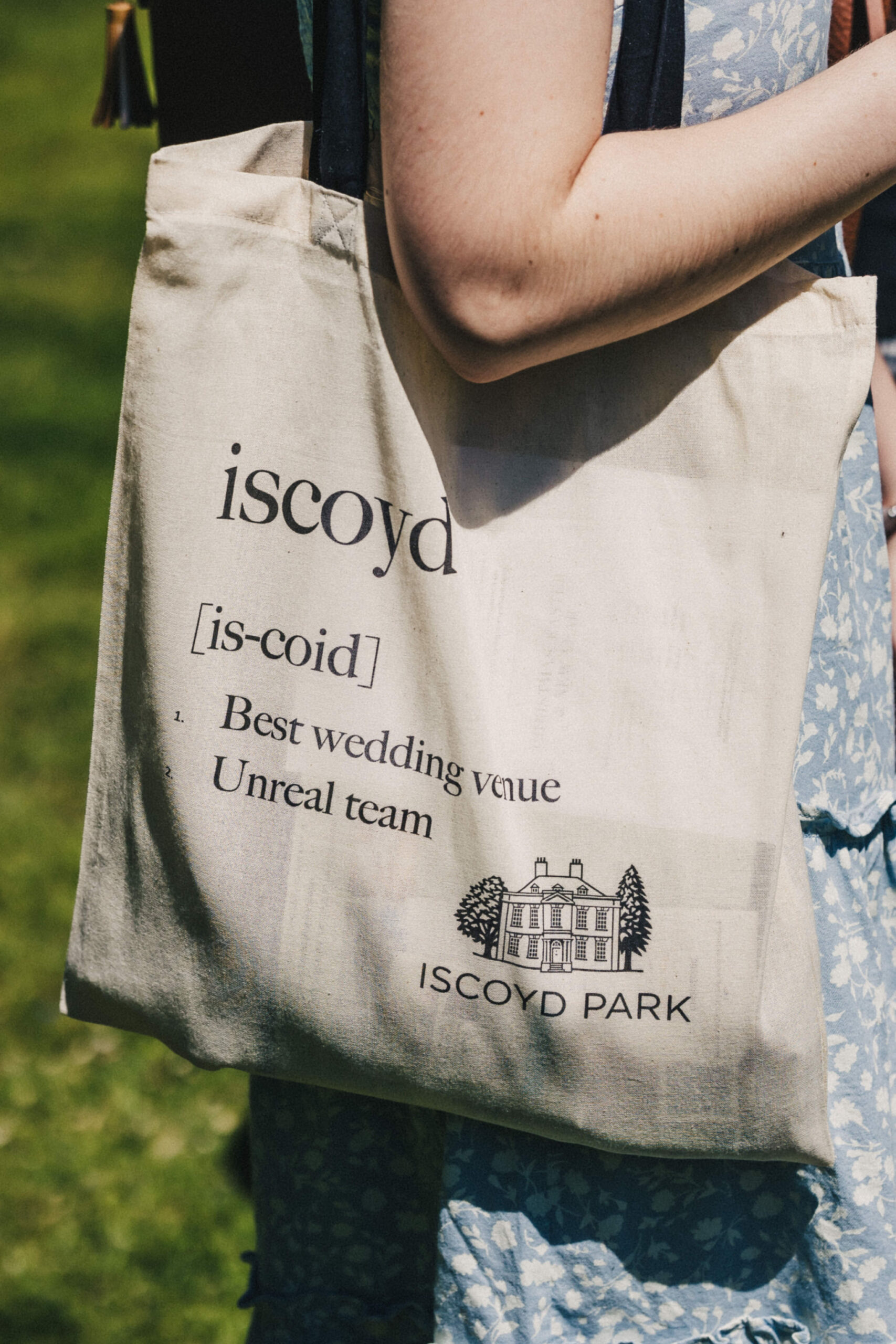 A tote bag hanging over the shoulder of a woman with the inscription 'iscoyd best wedding venue unreal team