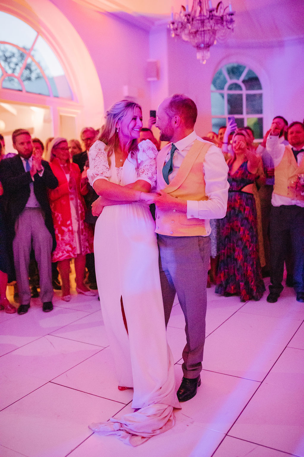A bride and groom take a spin on the dance floor whilst their guests look on