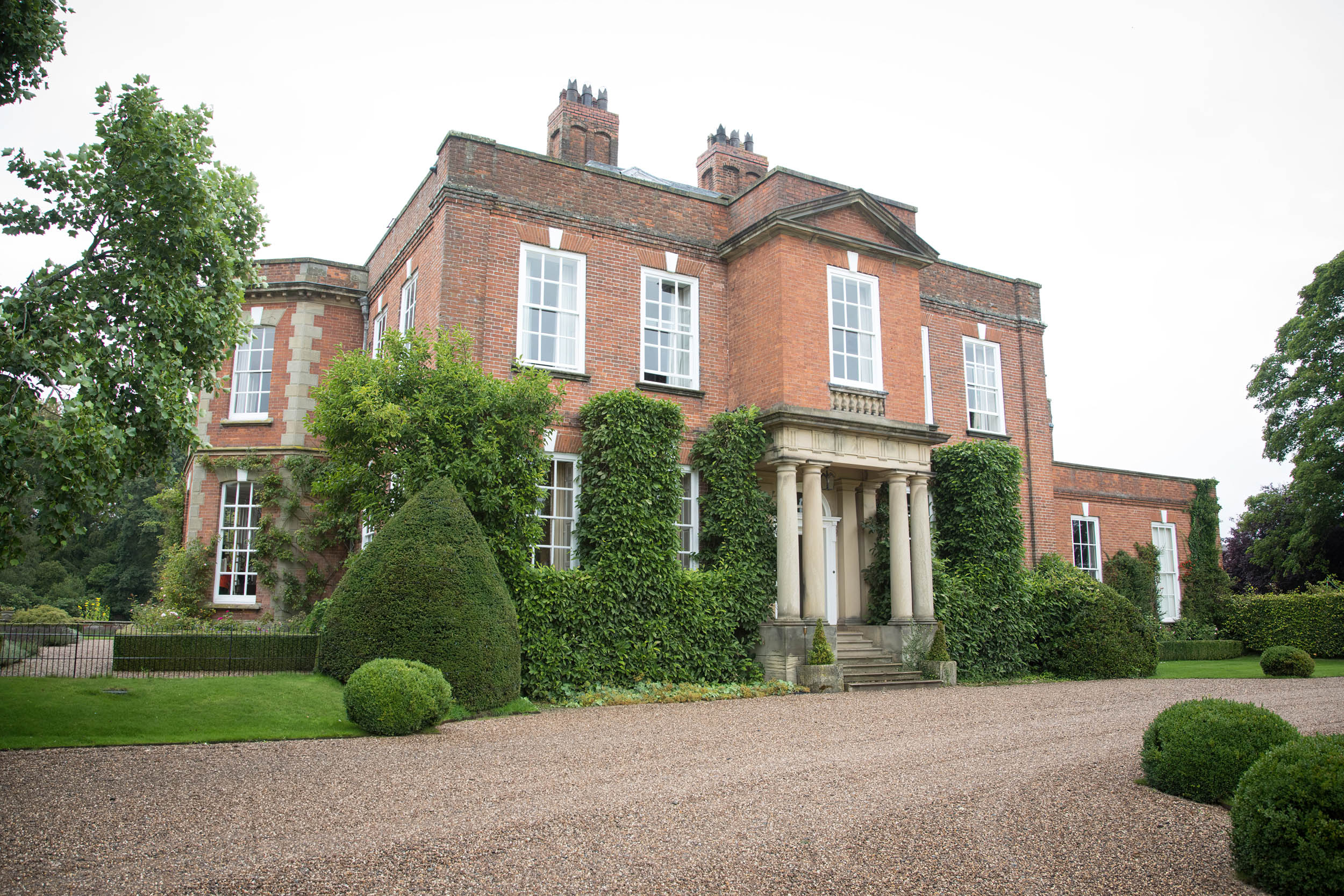 A landscape view of a handsome red brick mansion with a grand stone portico