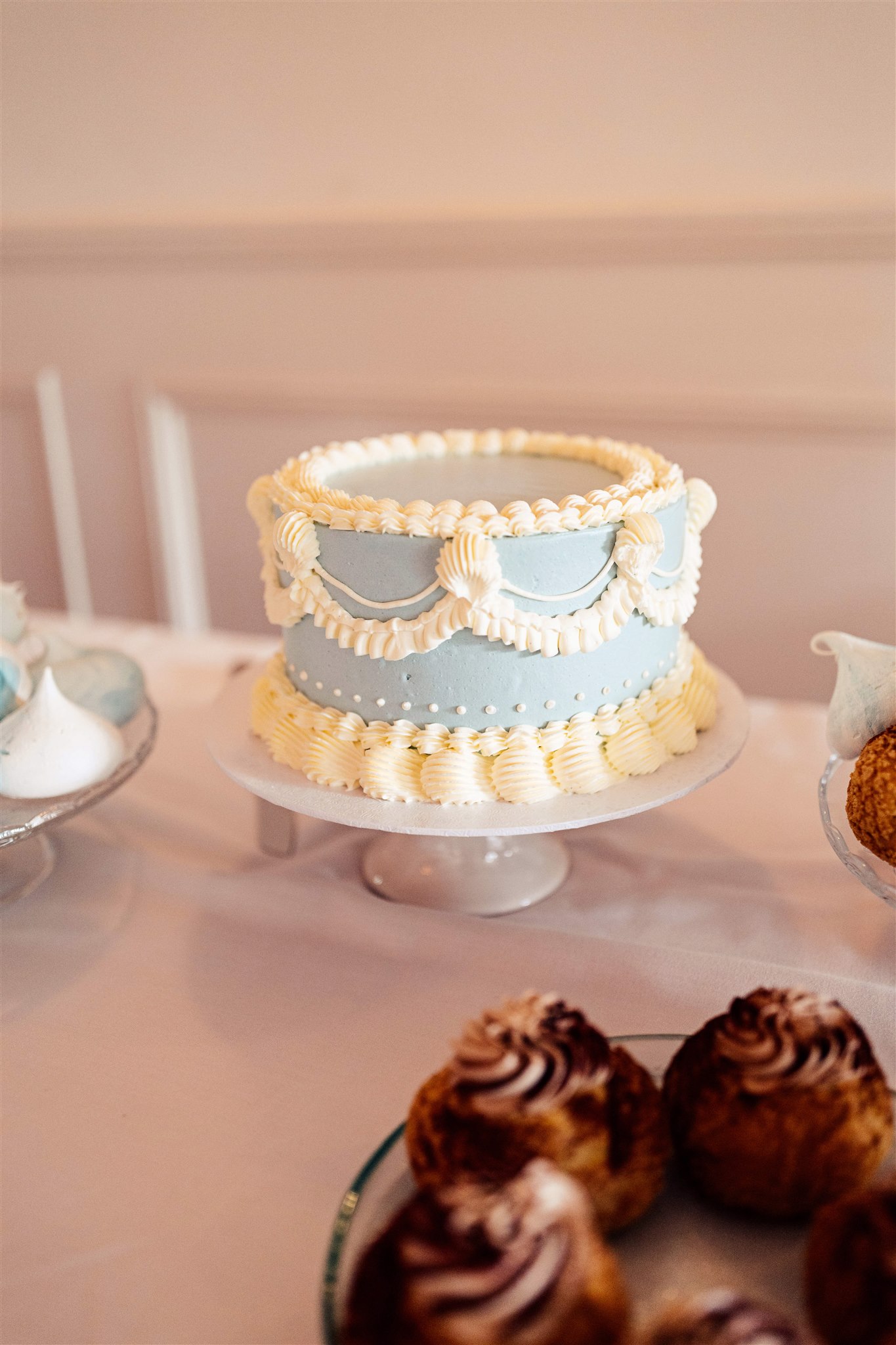 A blue and white elaborately iced wedding cake sits proudly on a table at a wedding