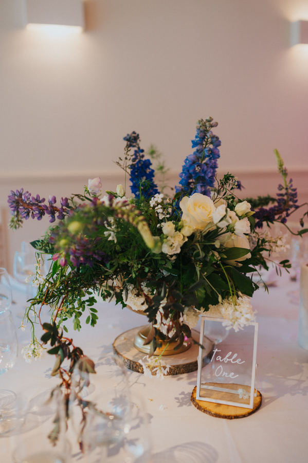 A beautiful floral arrangement sits on a table in a wedding reception