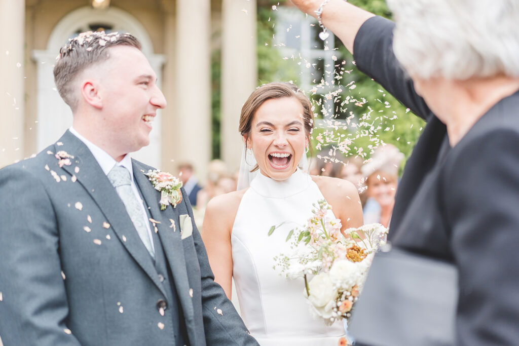 Hot coral wedding colour theme with a Justin Alexander halter neck wedding dress at luxury wedding venue Iscoyd Park by Sarah Horton Photography